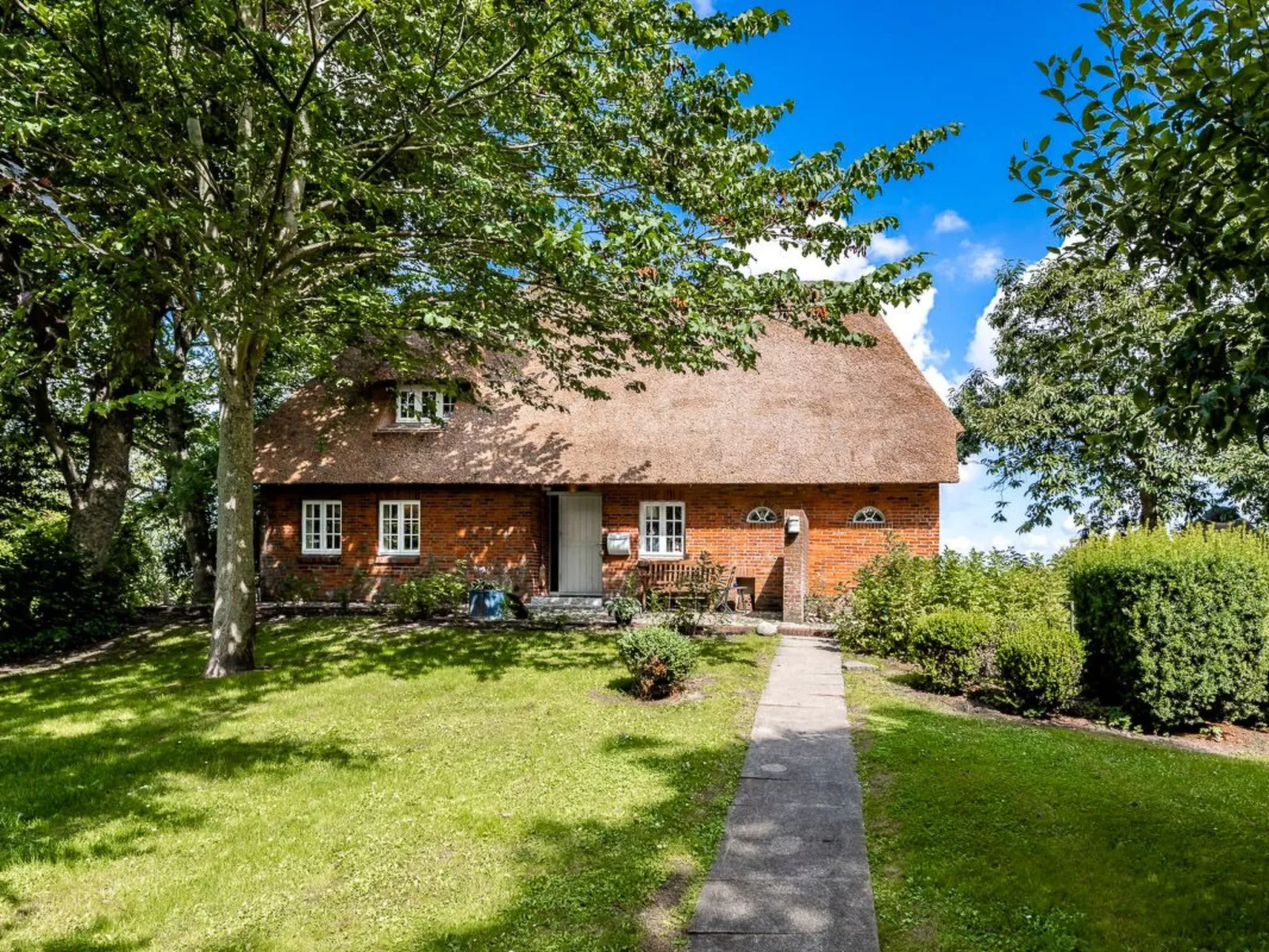 Reetdachhaus inmitten von Wiesen und Feldern